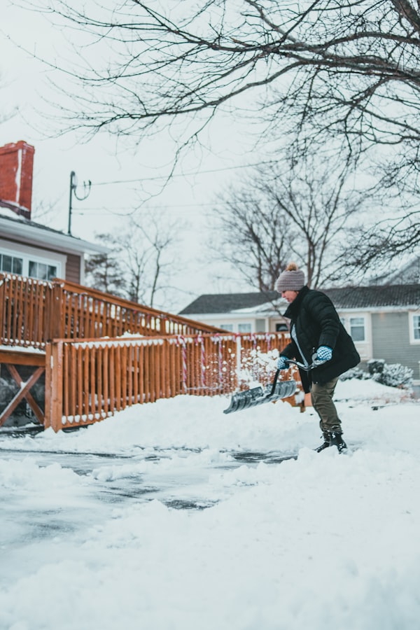Person schaufelt Schnee auf einem Gehweg im Winter